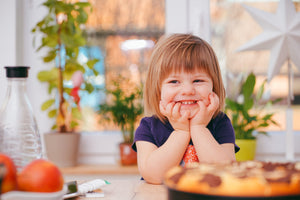 Little girl smiling sitting in front of plants